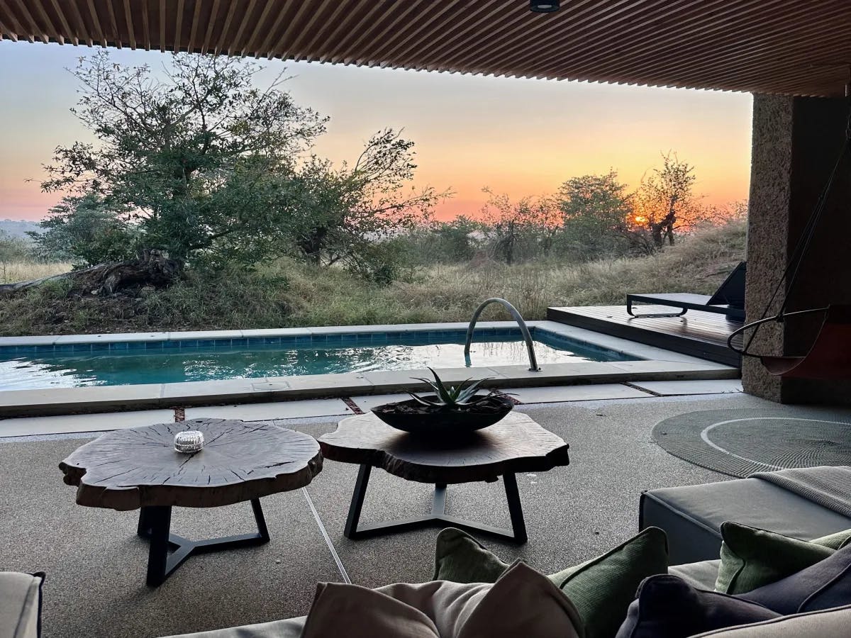 A tranquil poolside patio set against a backdrop of nature’s beauty at dusk.