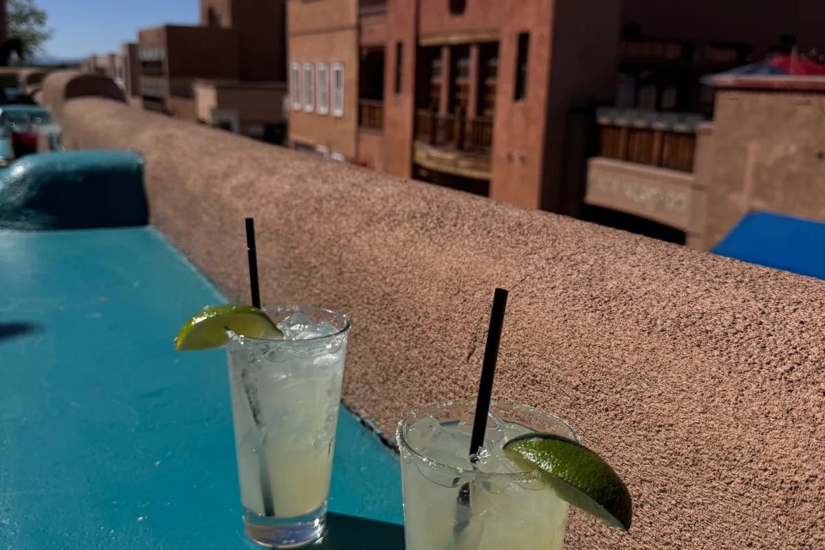 An image of two margaritas with lime on the bar by a stone ledge. 