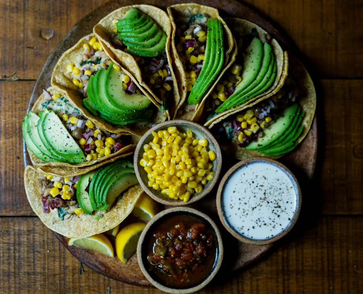 Tacos on a plate with avocado and salsa 