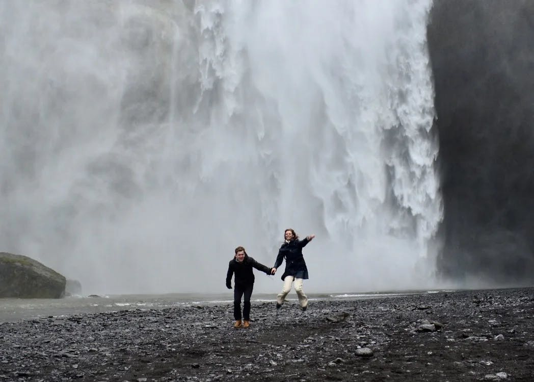 A man and woman in front of a waterfall. 