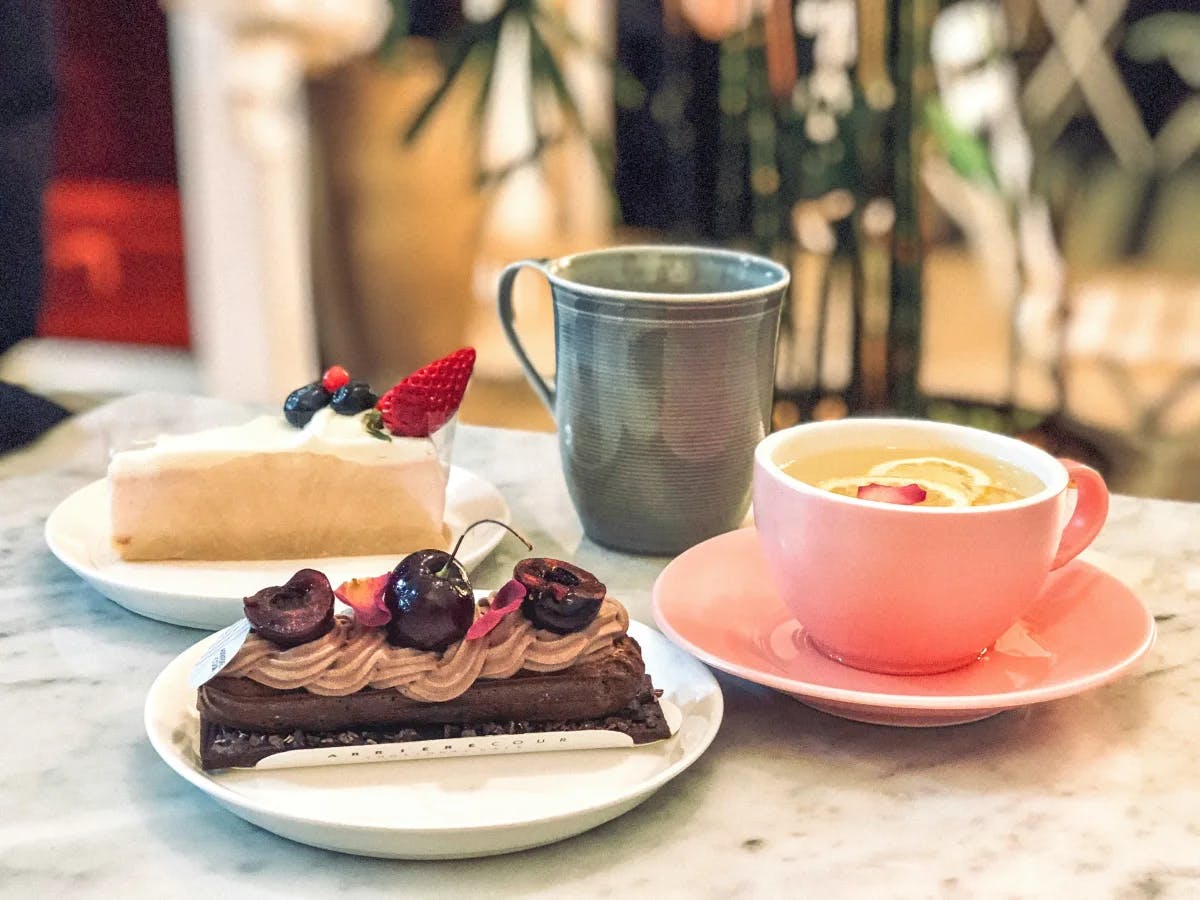 A table with two mugs and plates of pastries.