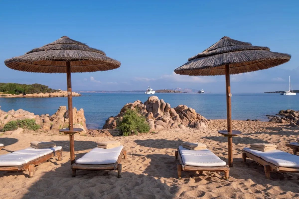 beach with thatched umbrellas and white loungers looking at the ocean