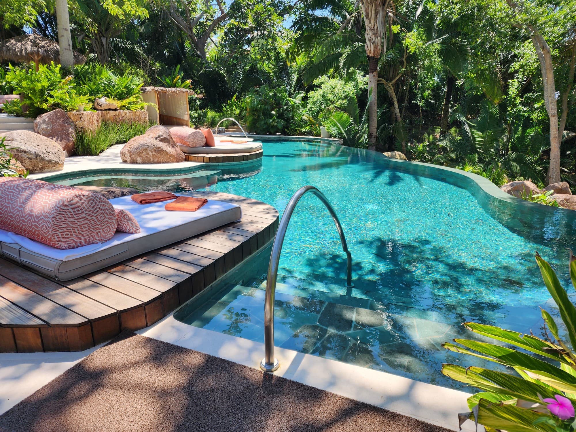 An outdoor swimming pool area surrounded by trees and greenery 