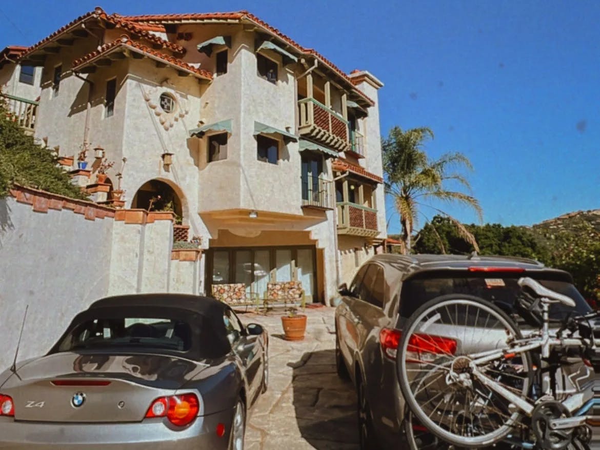 Off-white and orange building with cars in the front.