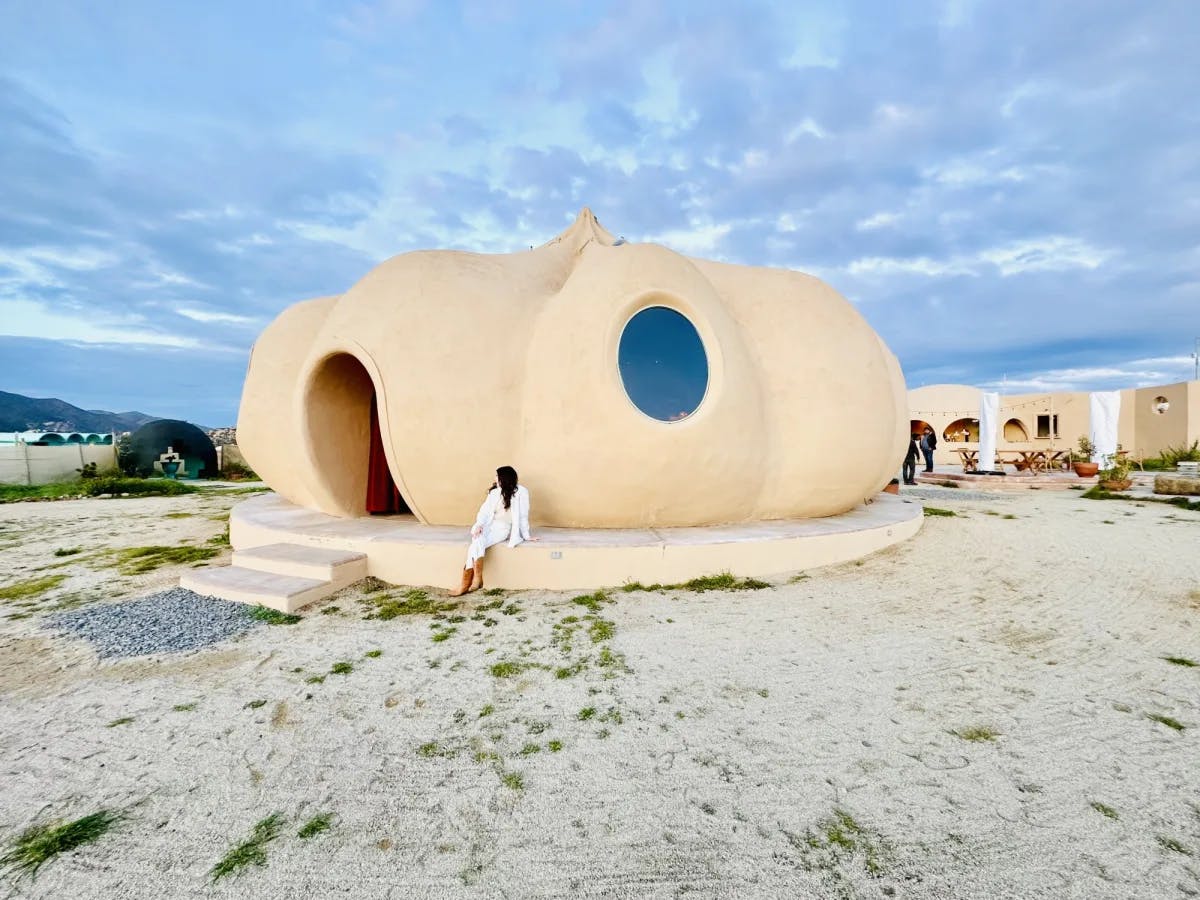 A woman sitting in front of pumpkin shaped building.