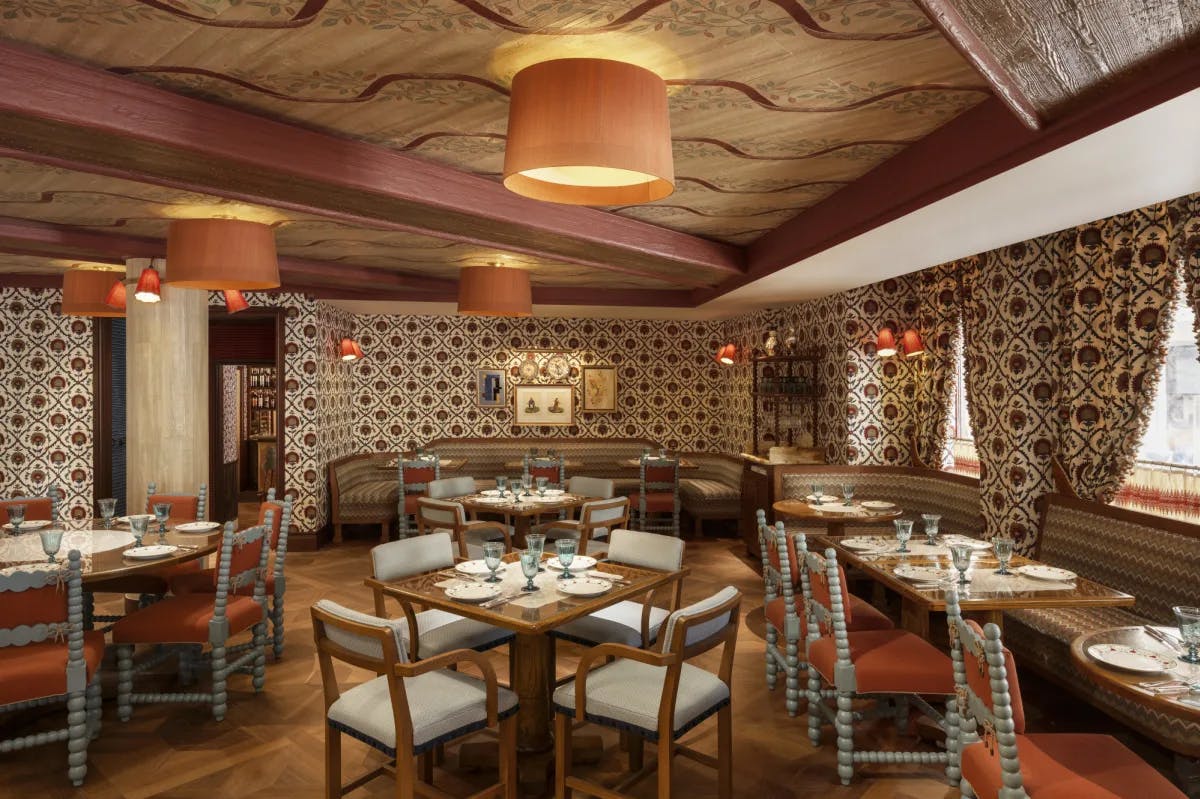 a colorful restaurant dining room with patterned wallpaper and drapes