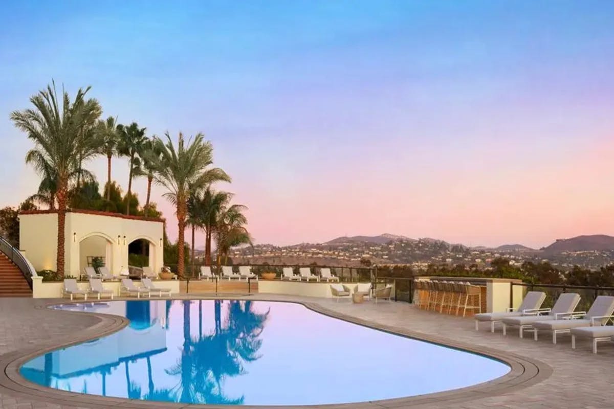 outdoor pool at sunset with lounge chairs and palm trees