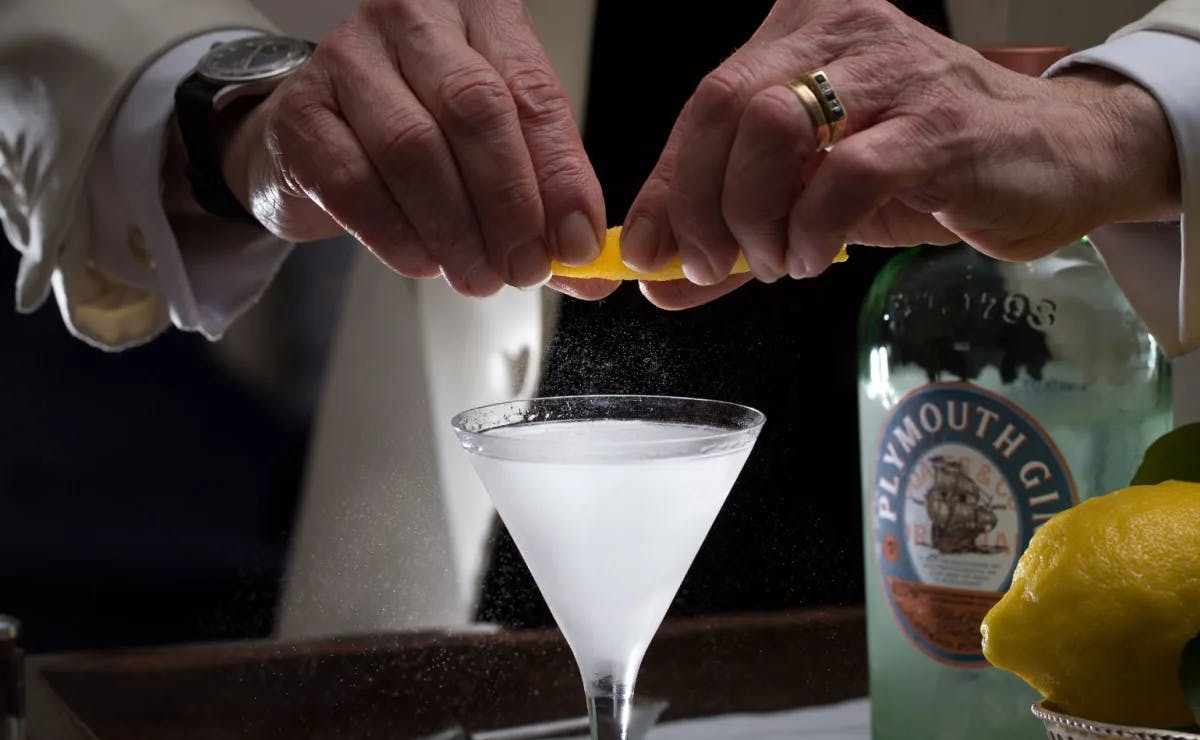 A drink in a martini glass with an orange fruit peel at London Dukes Bar. 