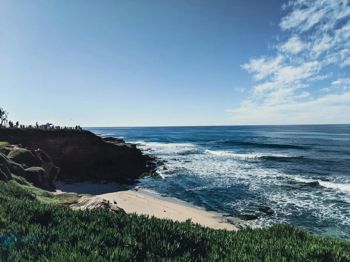 View of the ocean from the shore as waves lap the sands on a sunny day.