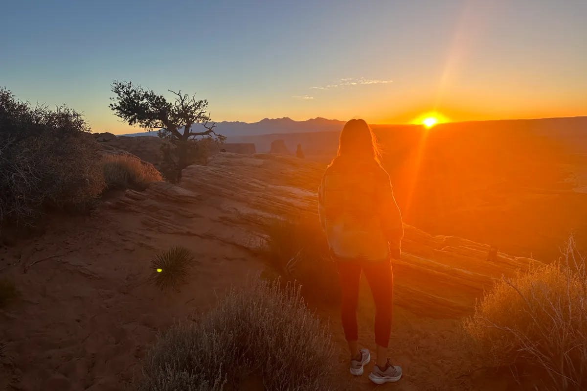 A picture of a girl watching the sunrise at Canyonlands.