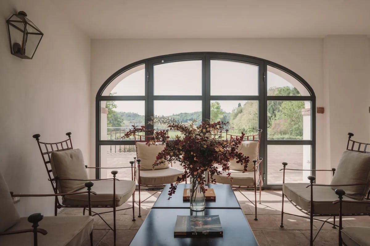 a fancy living room with a large bouquet of flowers and a large window overlooking a sprawling lawn