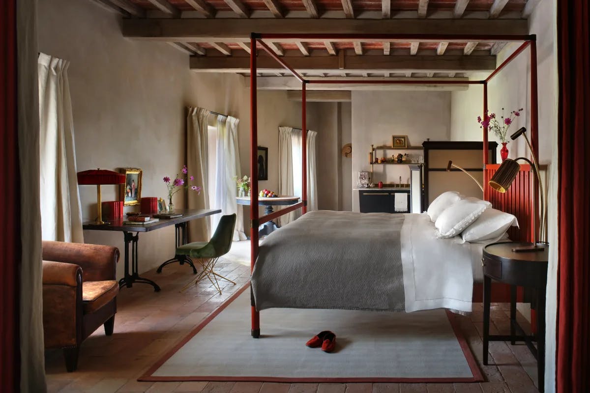 red velvet slippers sit at the base of a four-poster bed in a luxe rustic bedroom