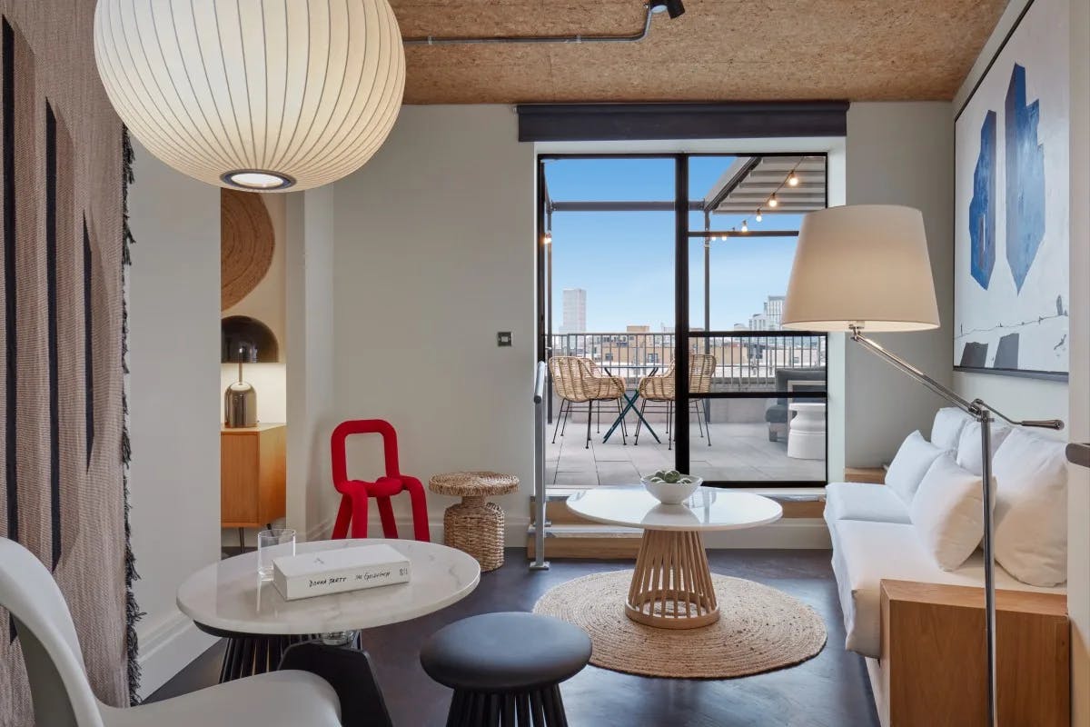 a modern loft living room with small round coffee tables and an artsy red chair