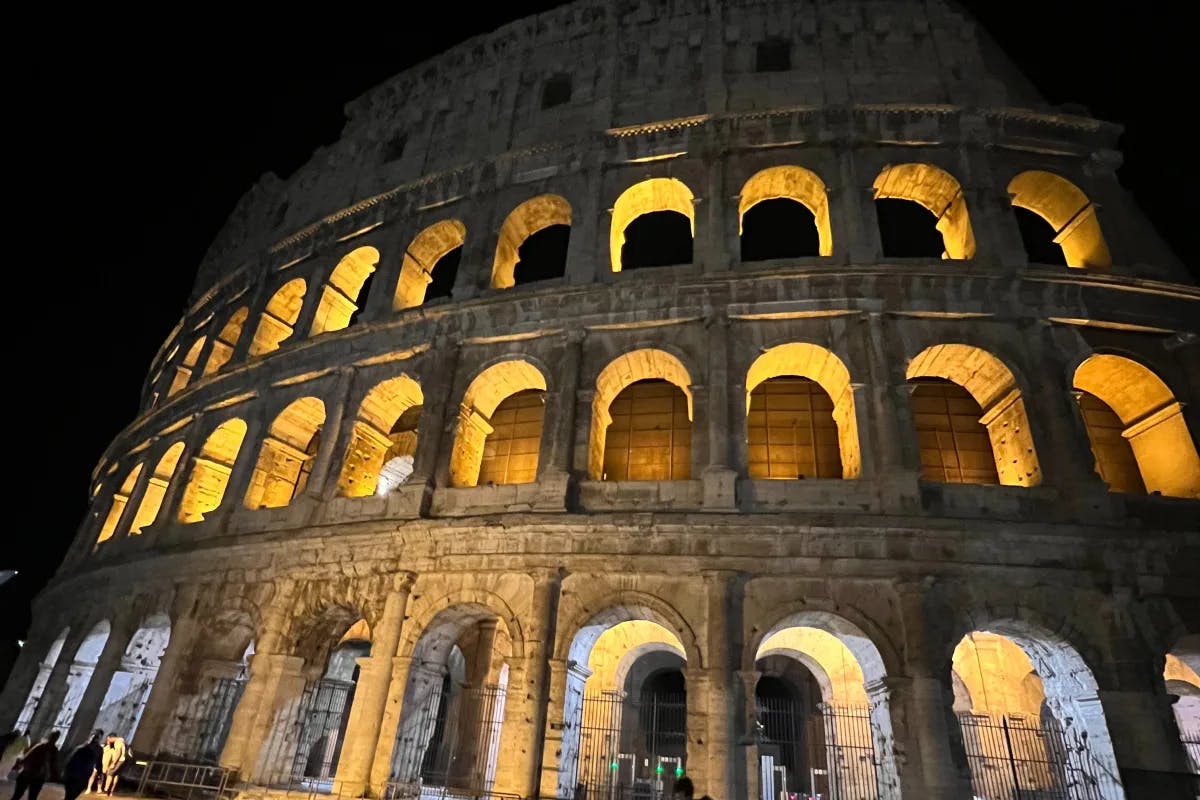 A low angled shot of the colosseum during the nighttime.