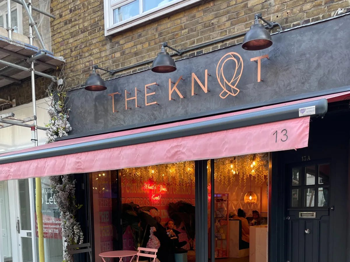 The outside of a cafe with a sign reading "The Knot" 