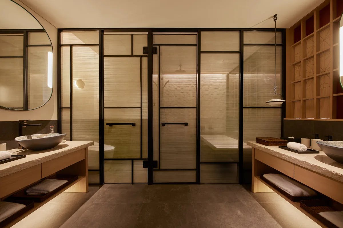 a luxe Japanese bathroom with stone sinks and bamboo dividers