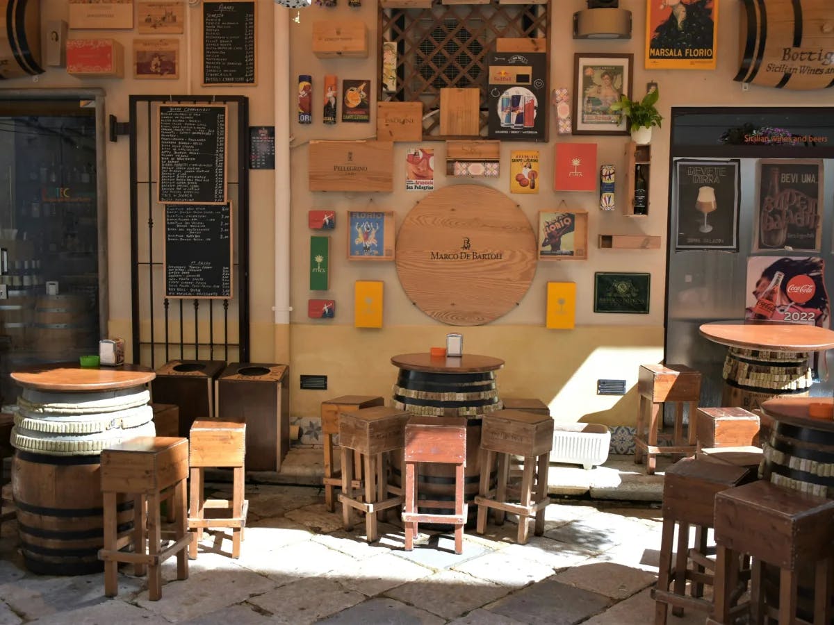 The image presents a quaint café’s outdoor seating, adorned with various signs and decorative items, creating a charming atmosphere.