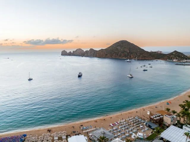 a beach with boats and a hill in the background