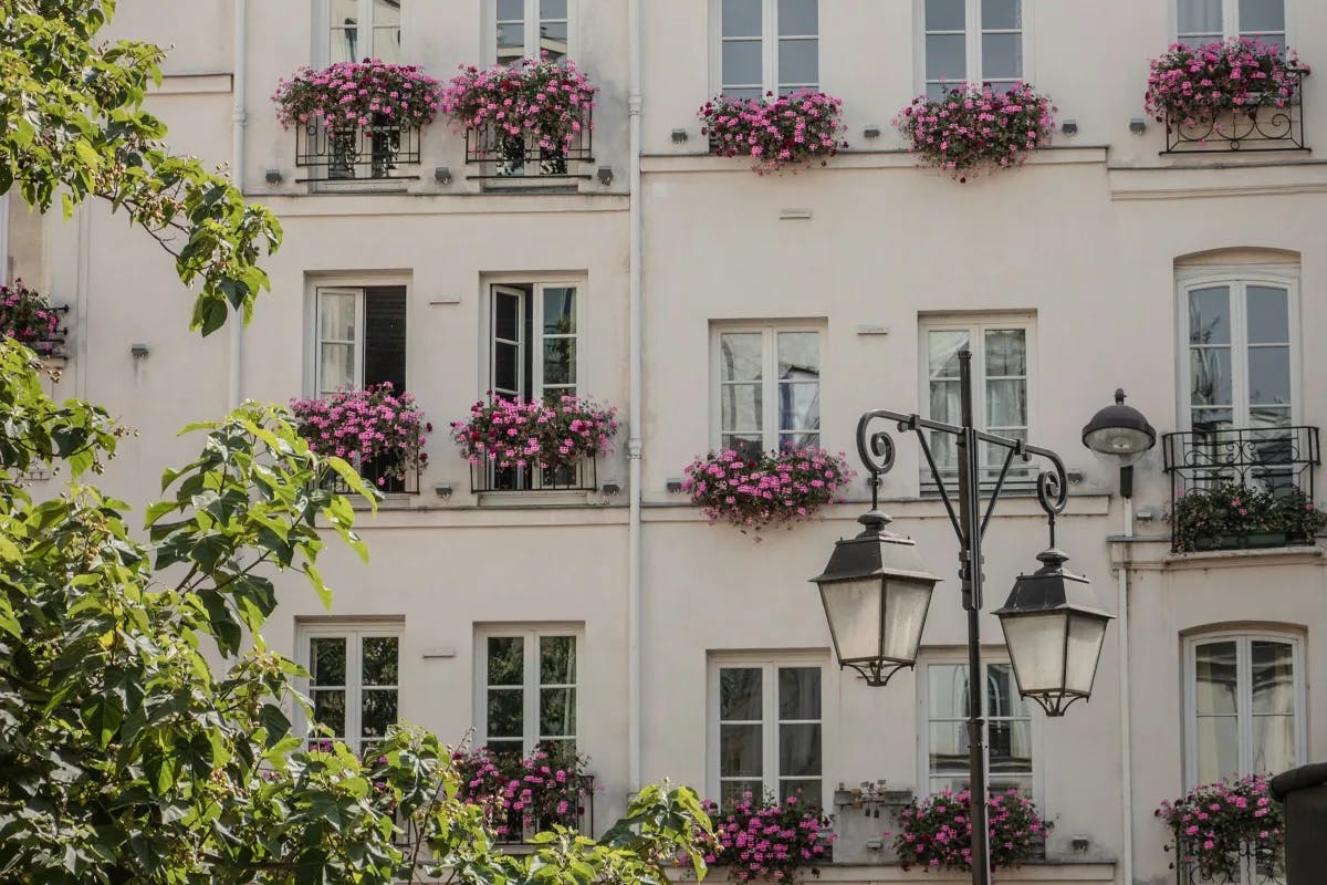 A building with flowers by the windows in Paris.