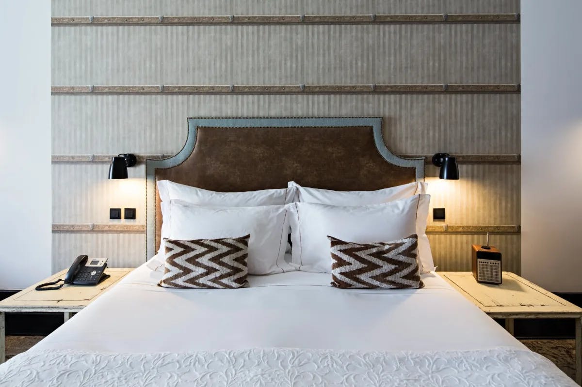 white bed with a brown headboard and bedside tables with lamps