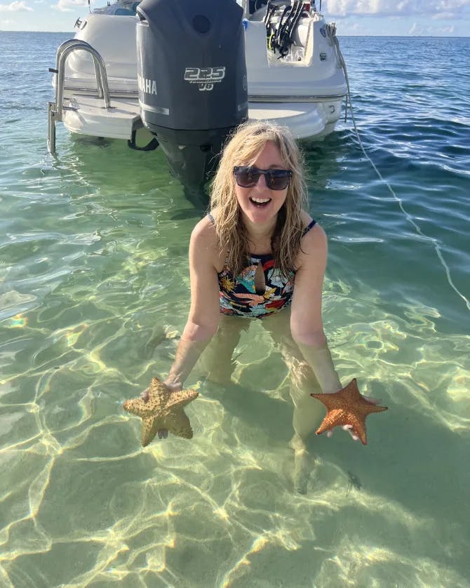 Wendy in the ocean holding two starfish from the sea before releasing them into the wild. 