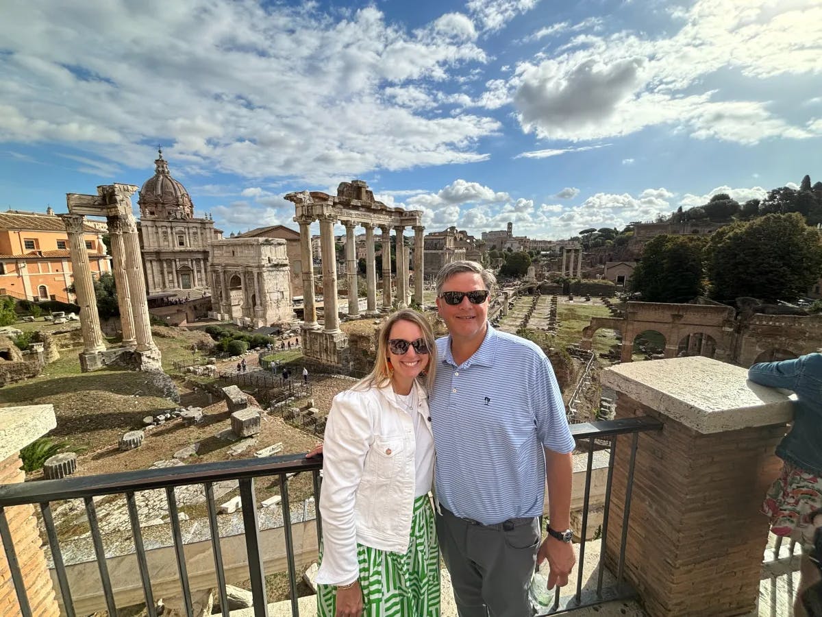 A couple posing for a photo in front of ancient ruins during the daytime