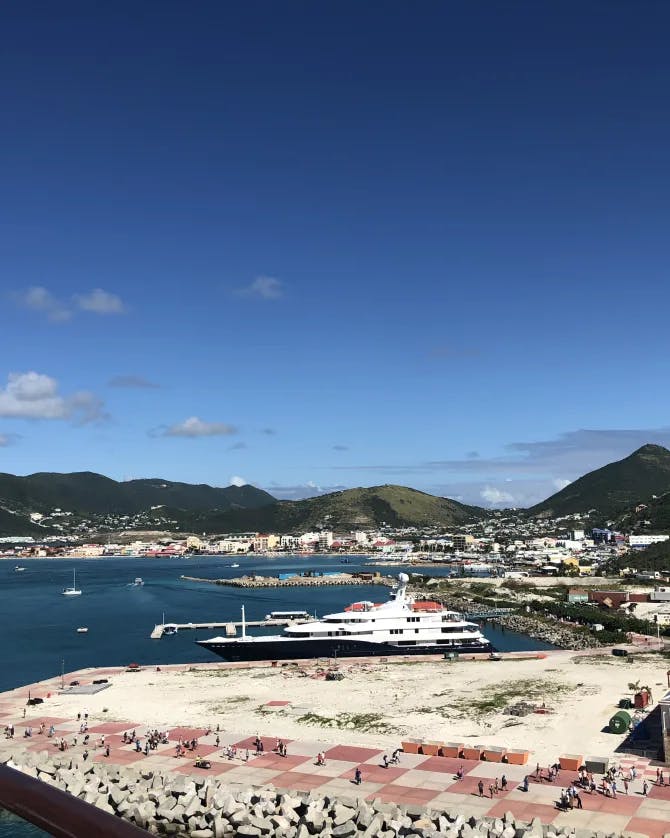 A picture of a cruise port with green mountains and blue water in the background