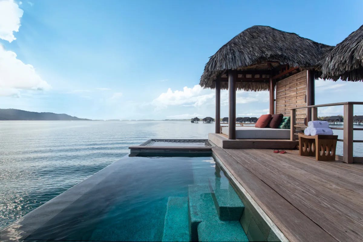 an overwater bungalow with an infinity pool and a wooden deck