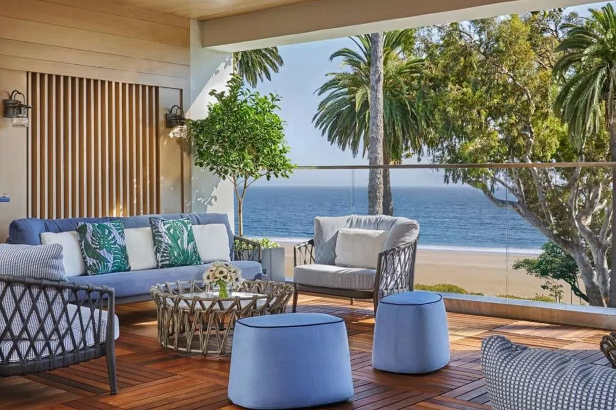 airy sitting area with blue and wood lounge chairs overlooking the ocean