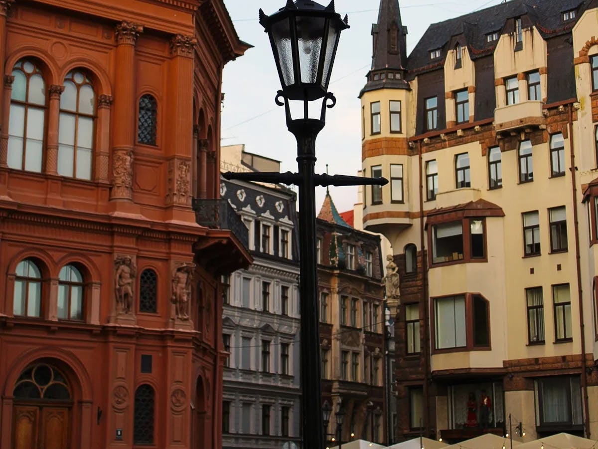 A street lamp in front of two old buildings with arched windows and warm-tones. 