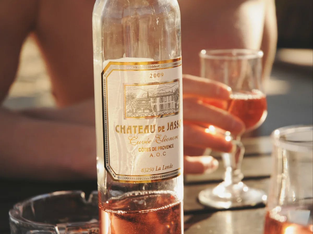 A bottle of Château de Jasson rosé from 2009 is bathed in sunlight, hinting at a leisurely outdoor gathering.