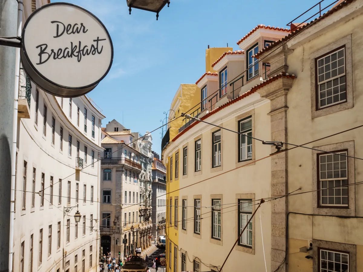 A city street with a restaurant sign reading "Dear Breakfast"