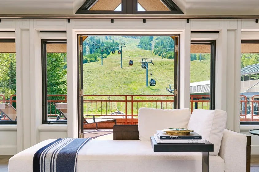 bedroom lounger in front of large window overlooking a green mountain with a chairlift