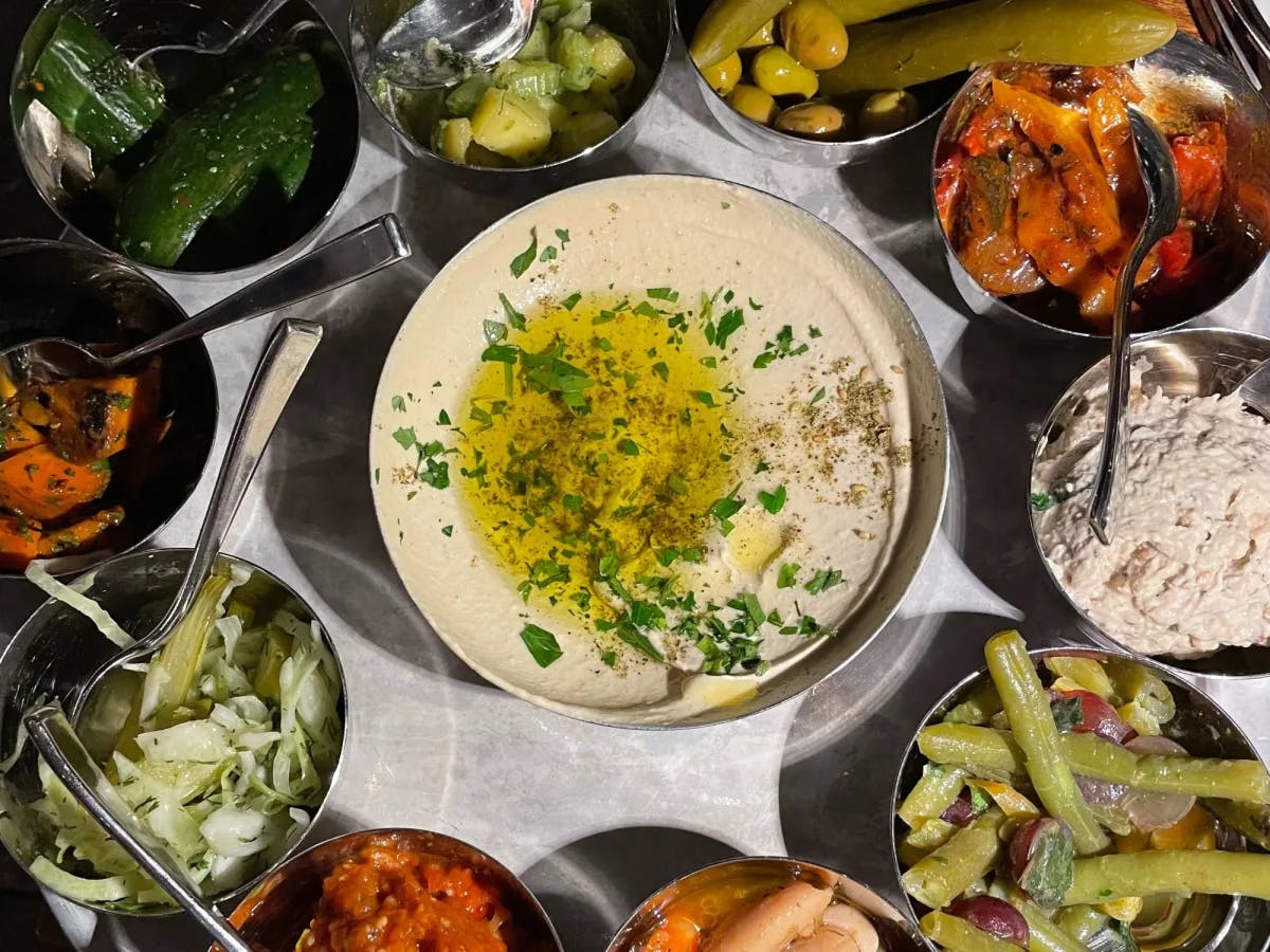 A food platter with different kinds of salads in small silver bowls.