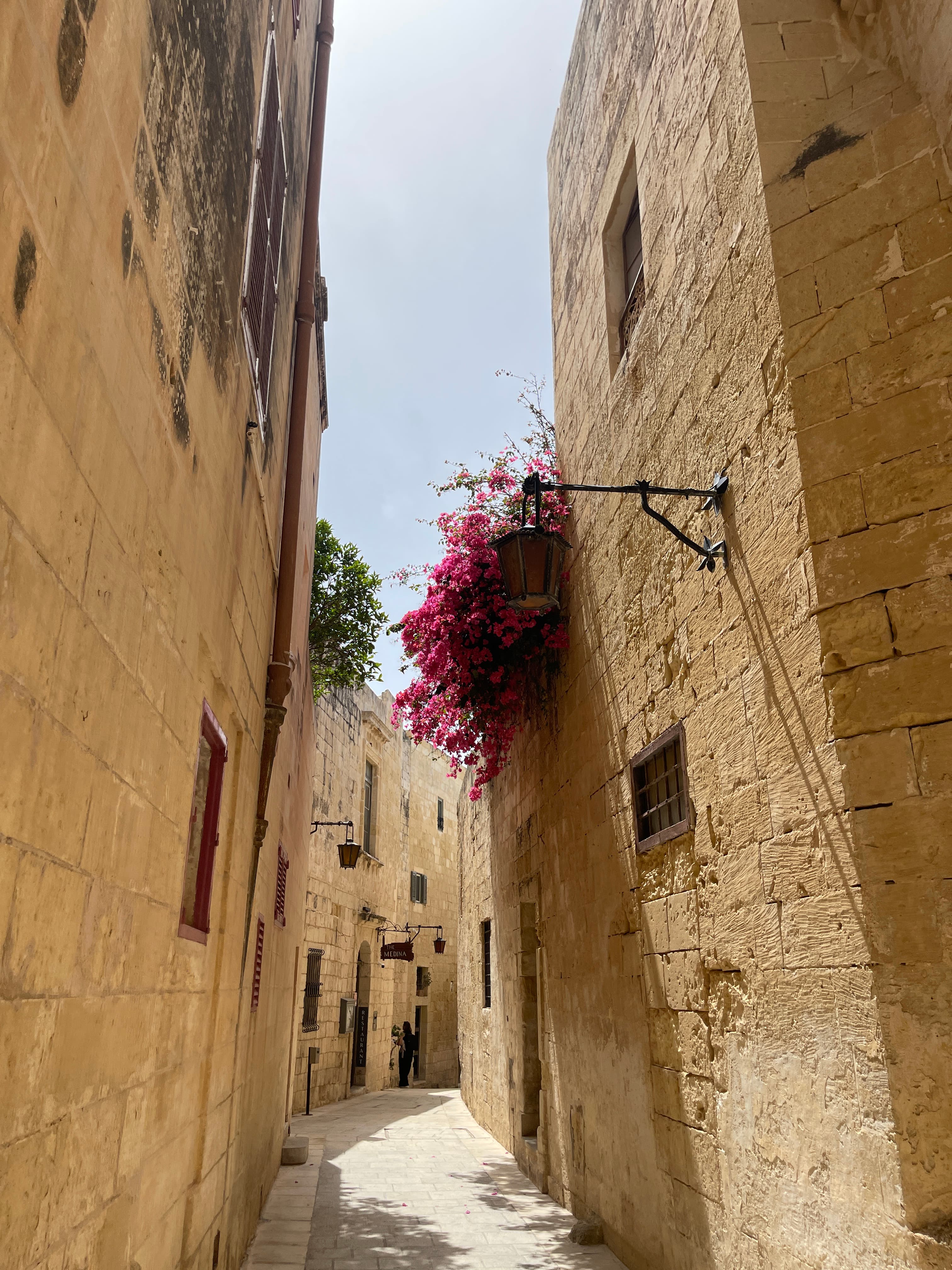 View of a narrow street in between old stone buildings on a sunny afternoon
