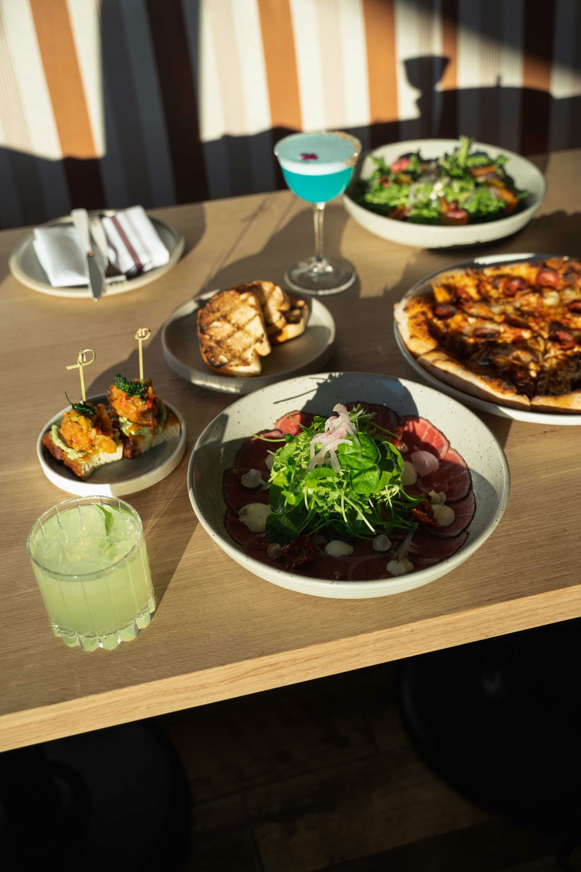 A variety of dishes on a table, illuminated by natural light, create an inviting dining scene.