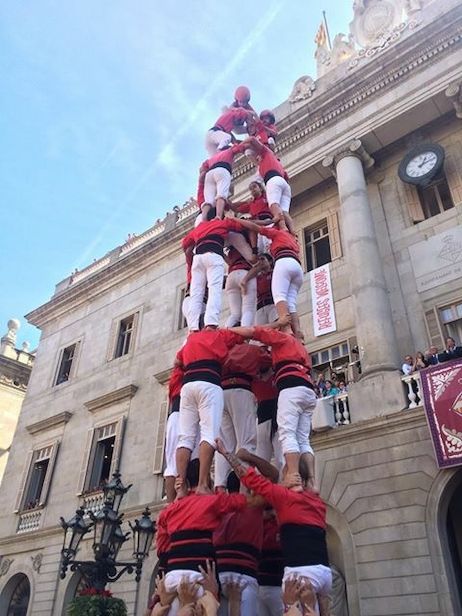 A group of people forming a human tower in front of a classical building