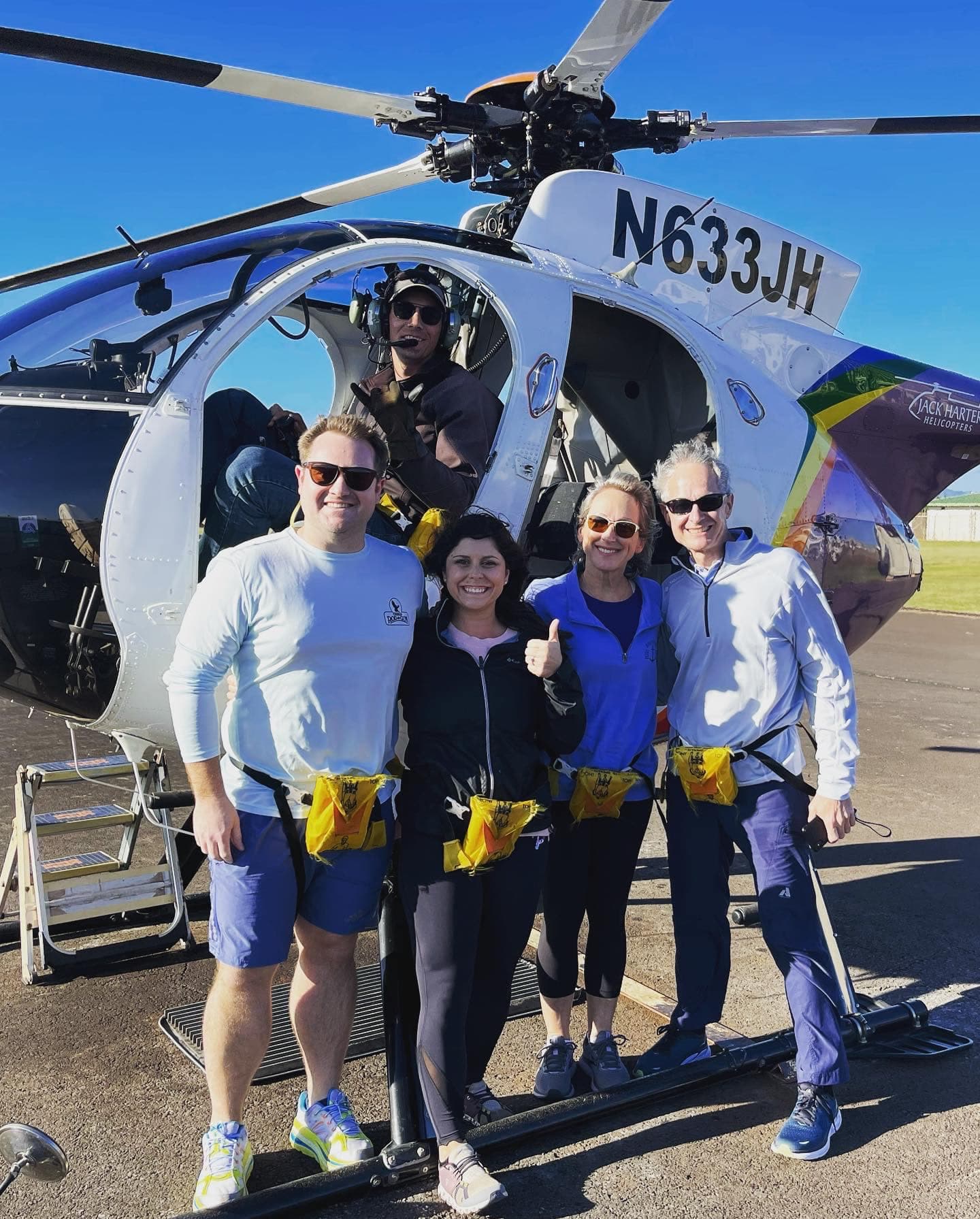 A group of people posing for a photo together in front of a helicopter