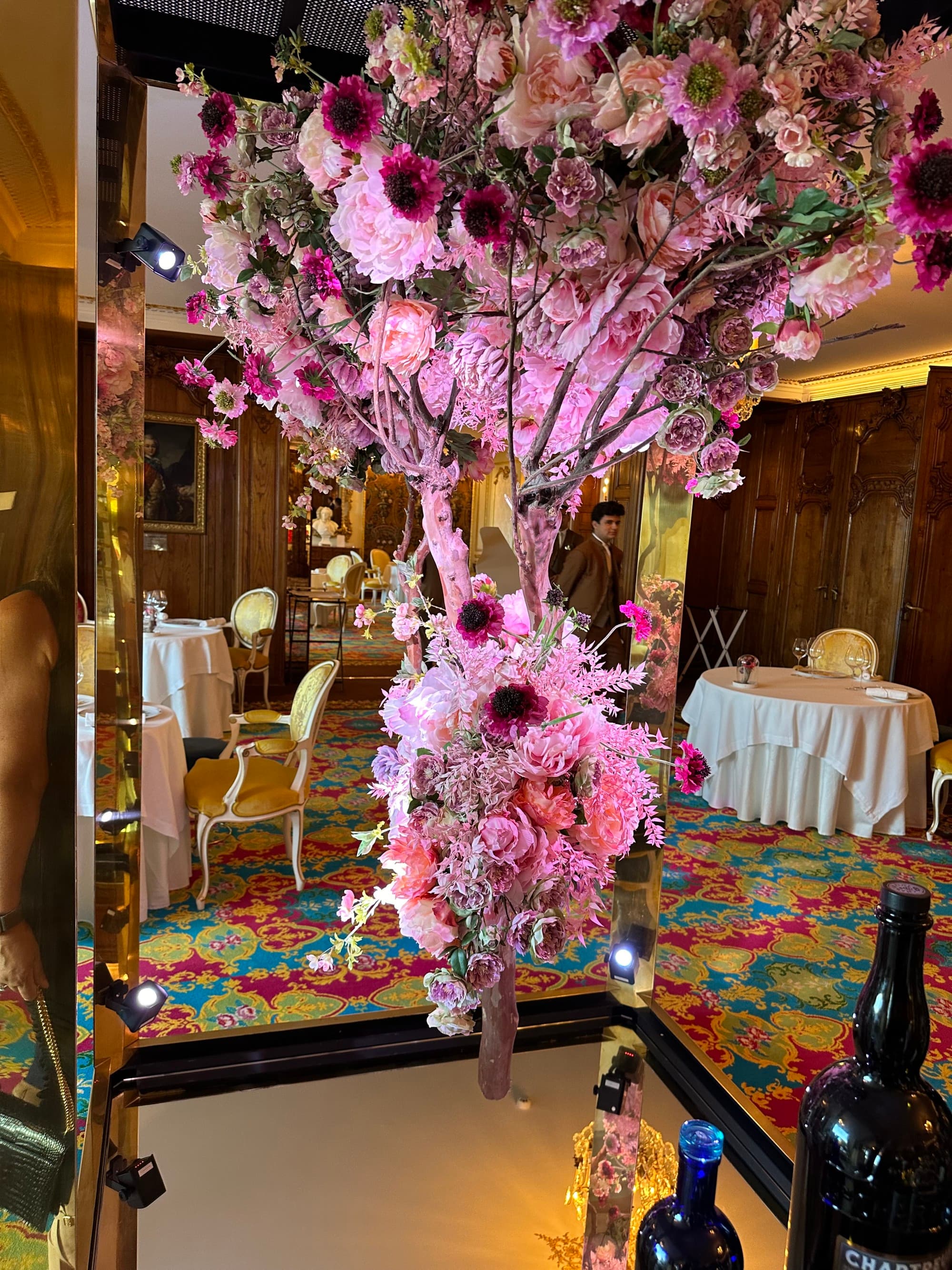 A vibrant floral arrangement with pink flowers in an eclectic interior space.