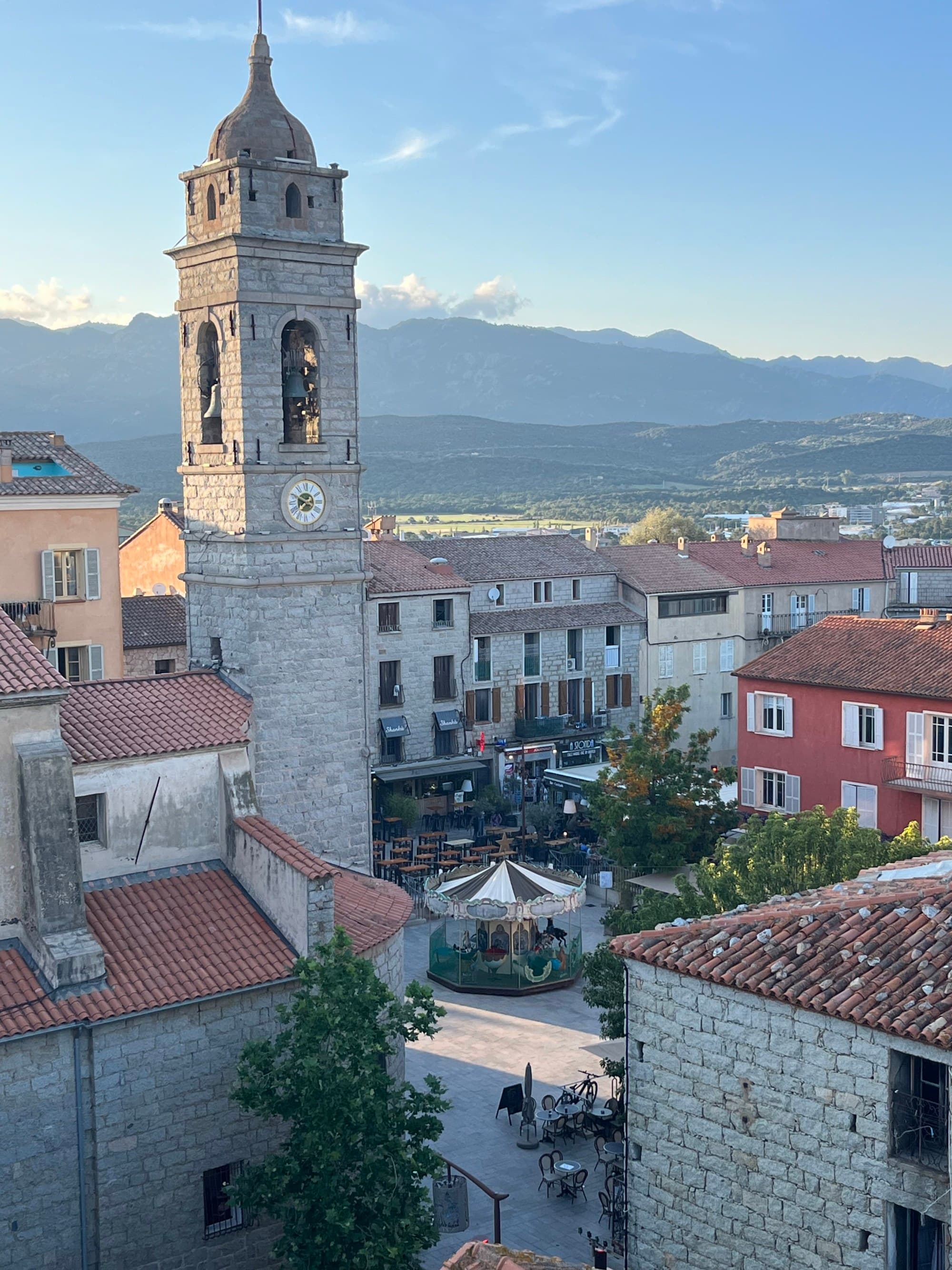 Buildings with mountains stretching toward the horizon in the distance on a sunny day.