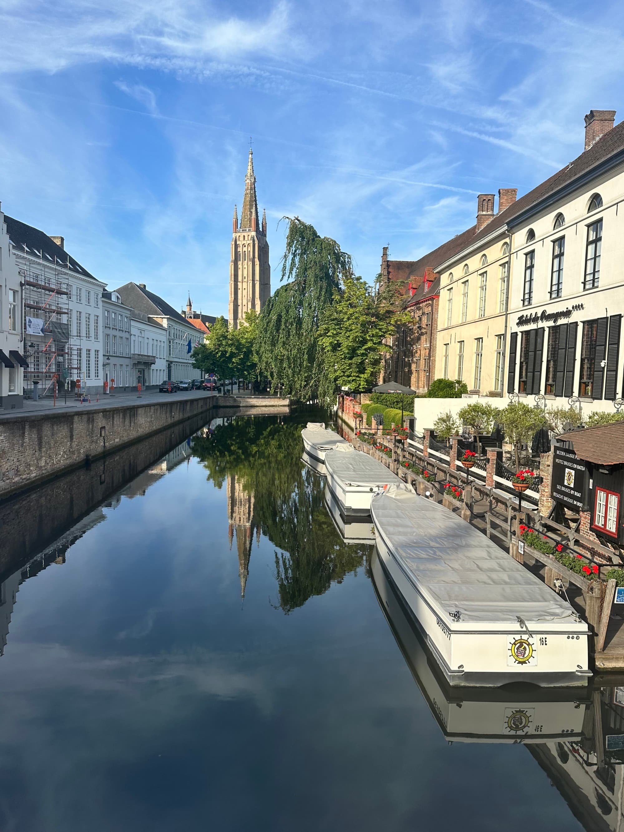 A European street scene is reflected upside-down in the water, showing buildings and a church spire under clear skies.