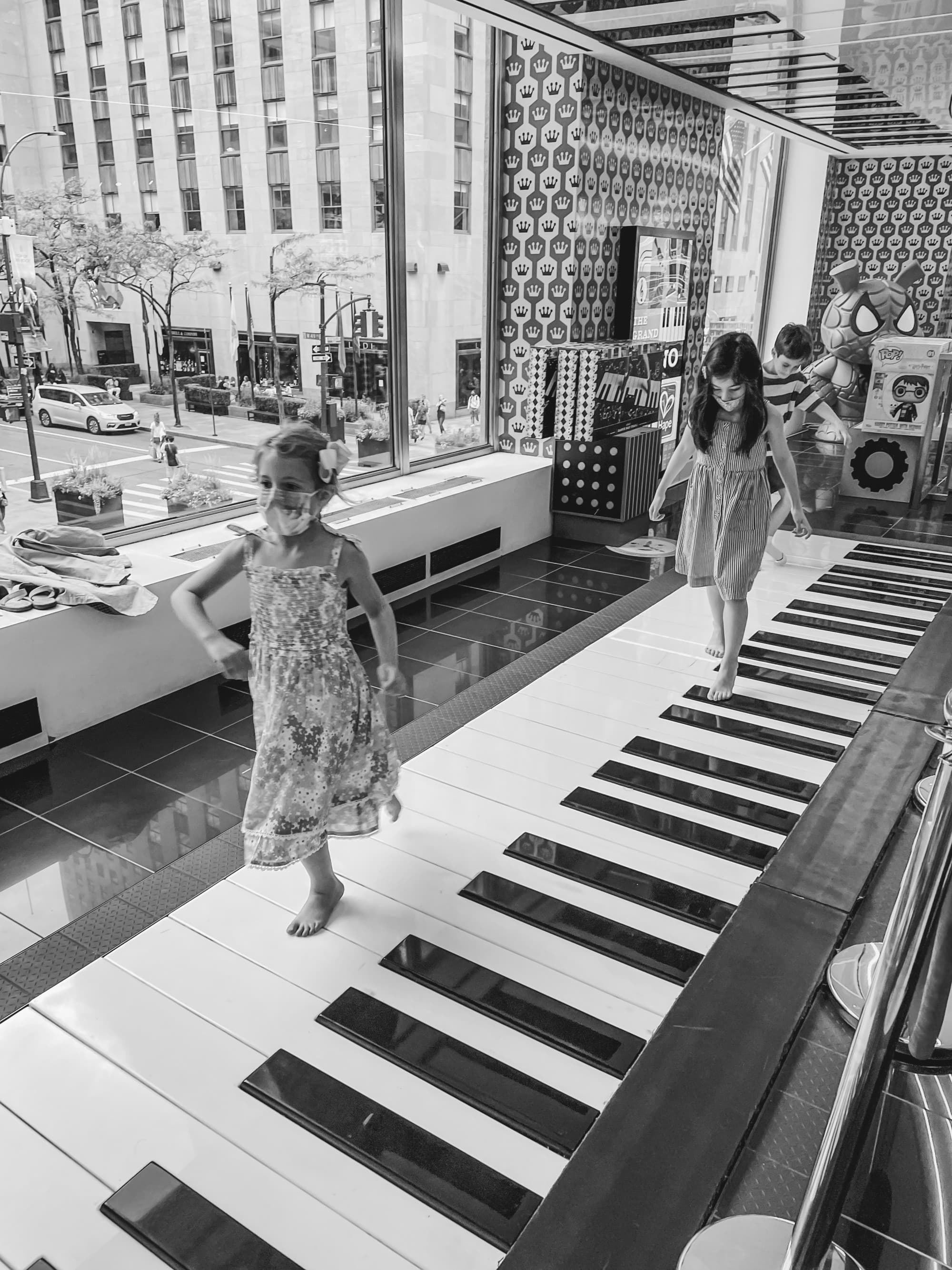 Kids walking over a big piano.