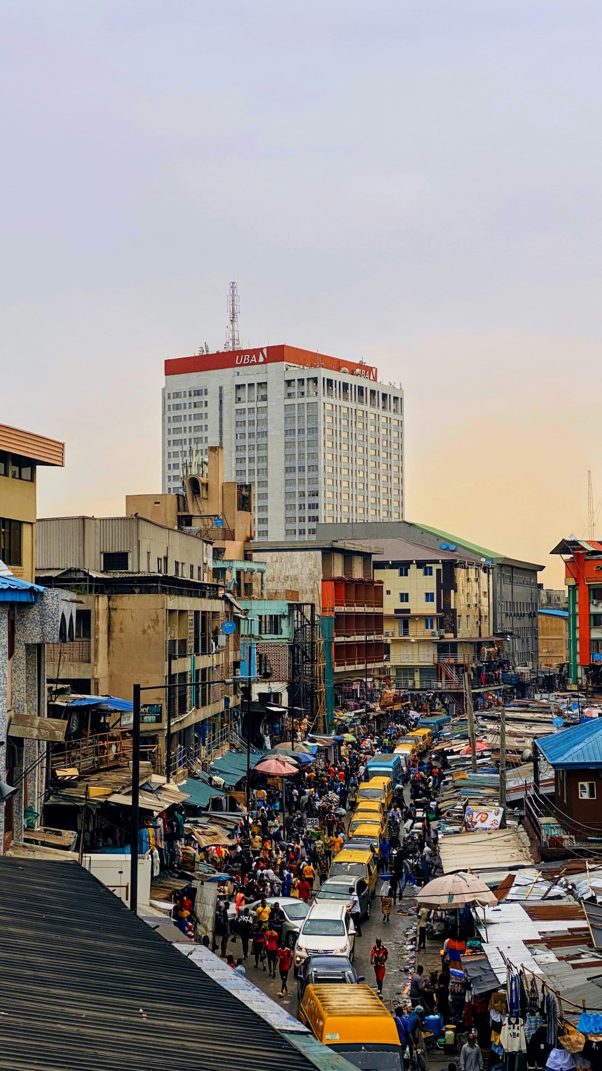 A vibrant street market bustling with activity, overlooked by a tall building.