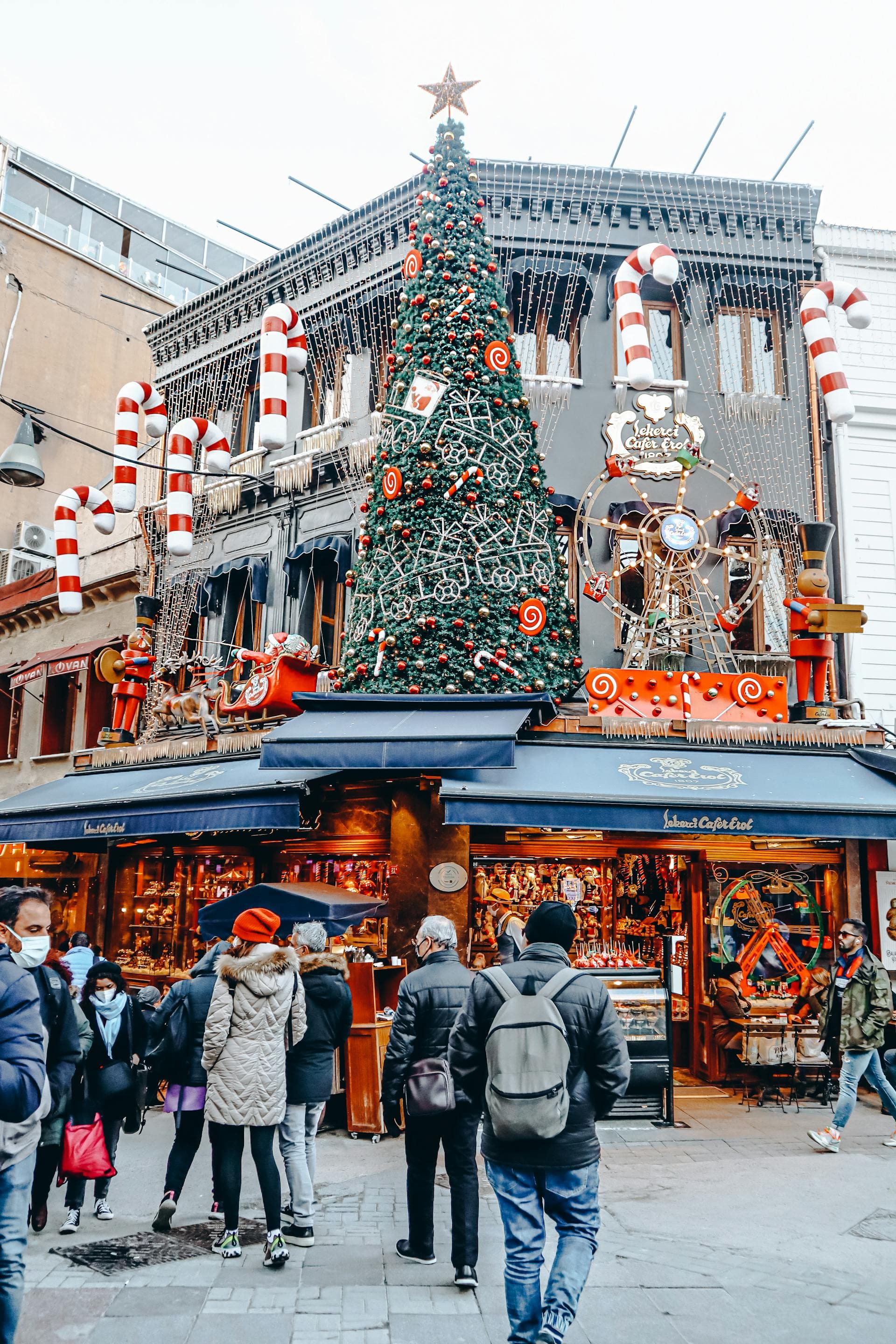 The front of a store decorated for Christmas with a large, fake Christmas tree and candy cane decorations