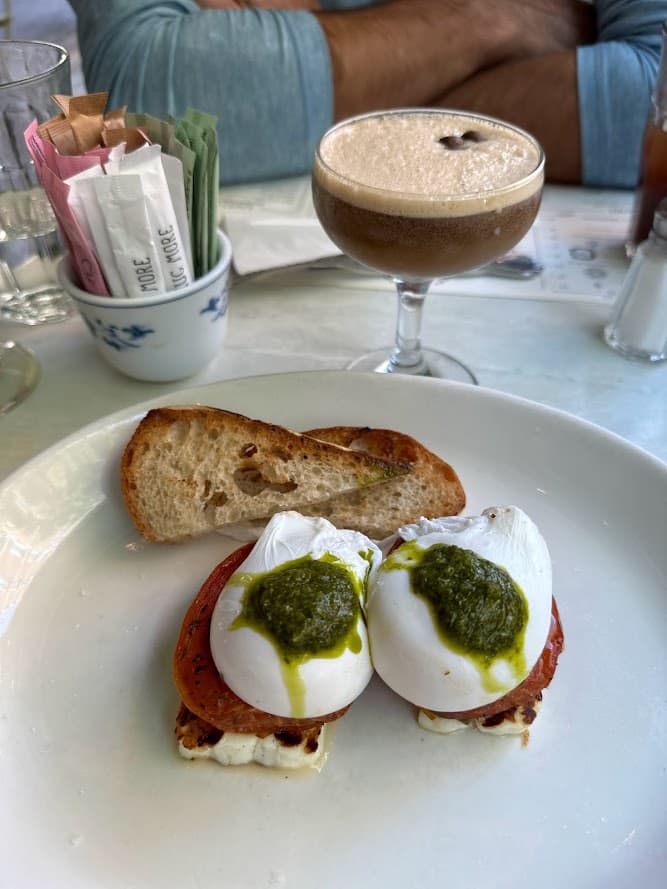 Breakfast food on a plate with a martini next to it on a table