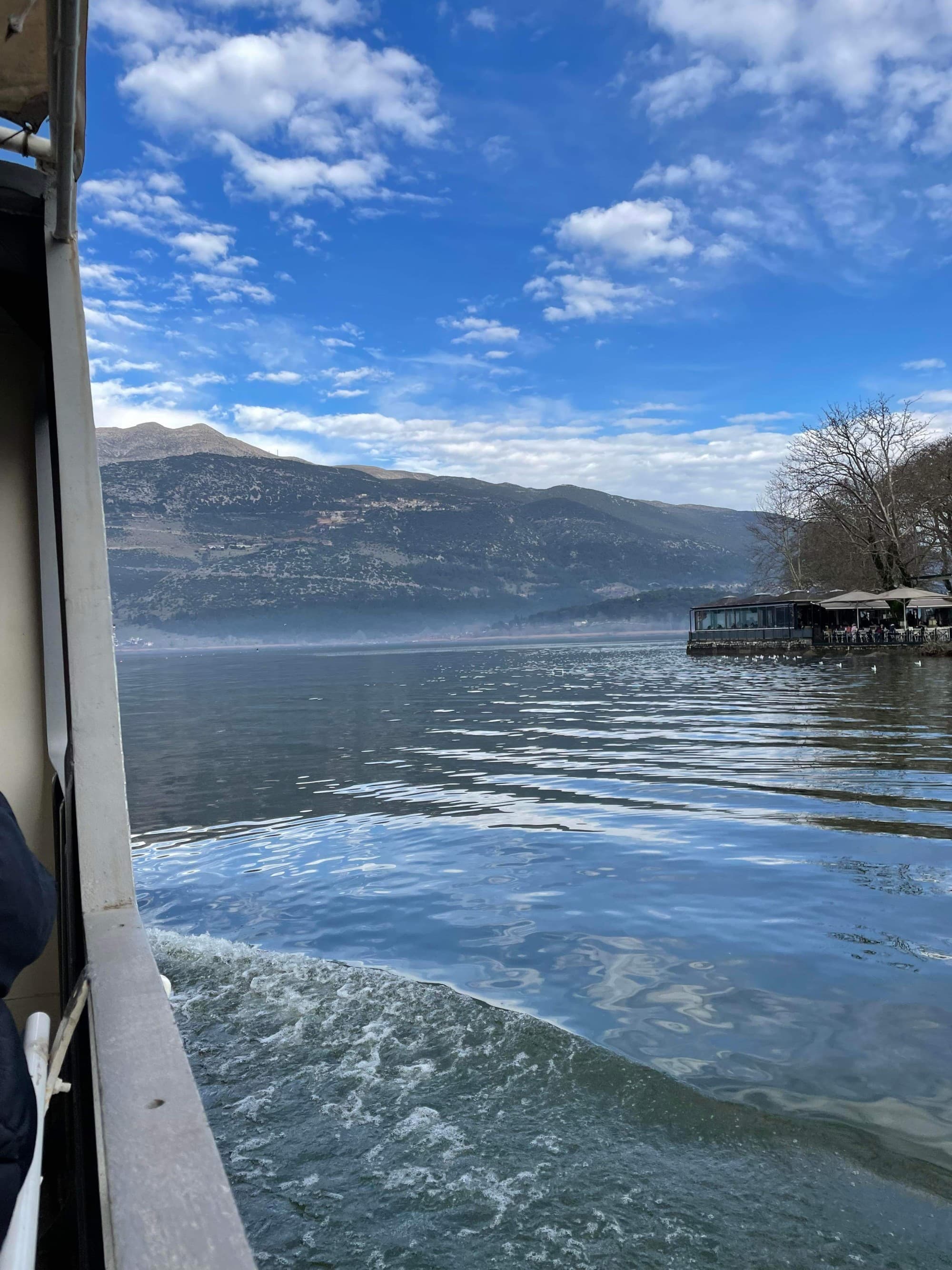 A boat moving through a river with a mountain in the background during the daytime