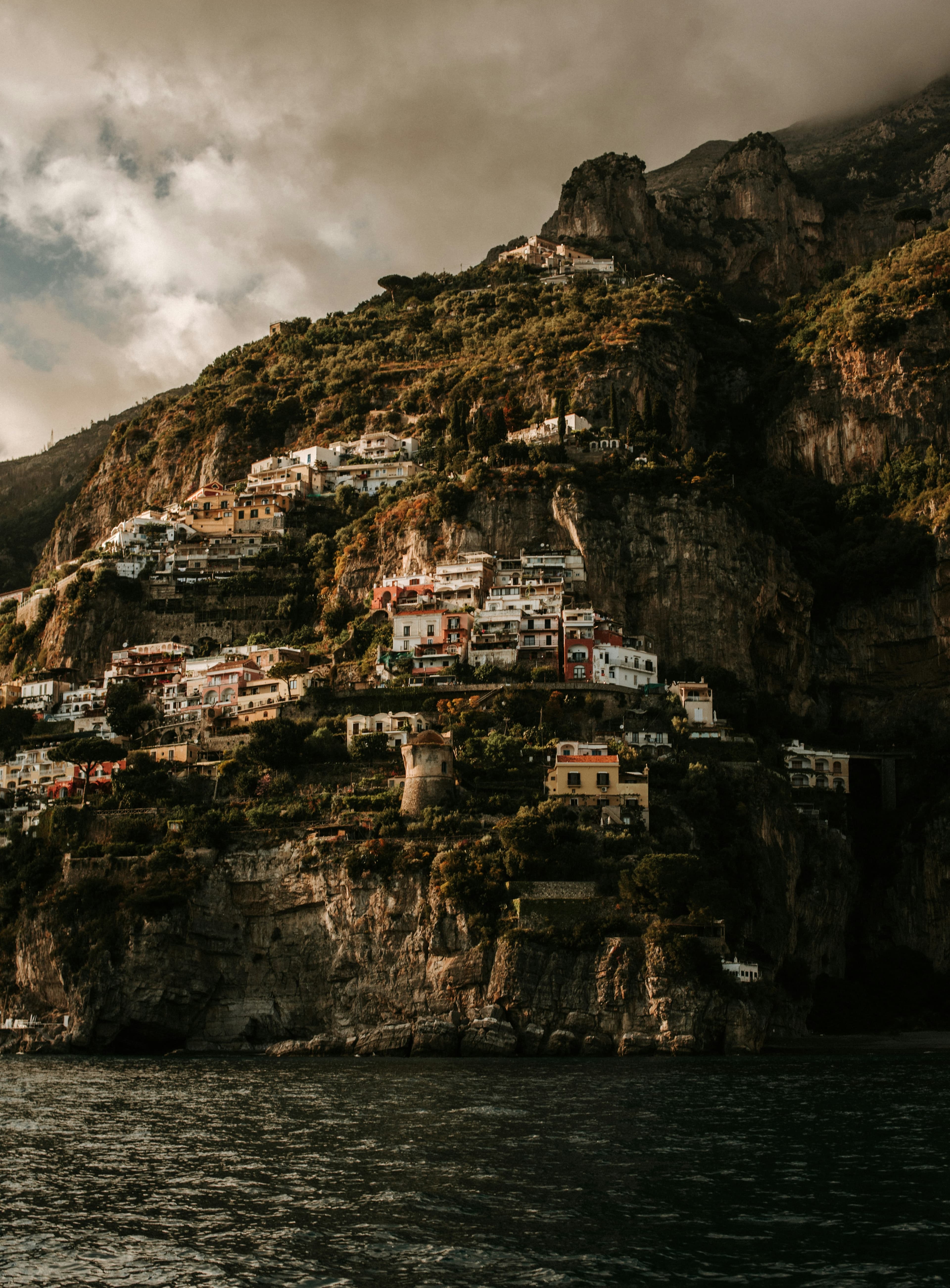 Small colorful houses perched on a rocky Italian cliff.