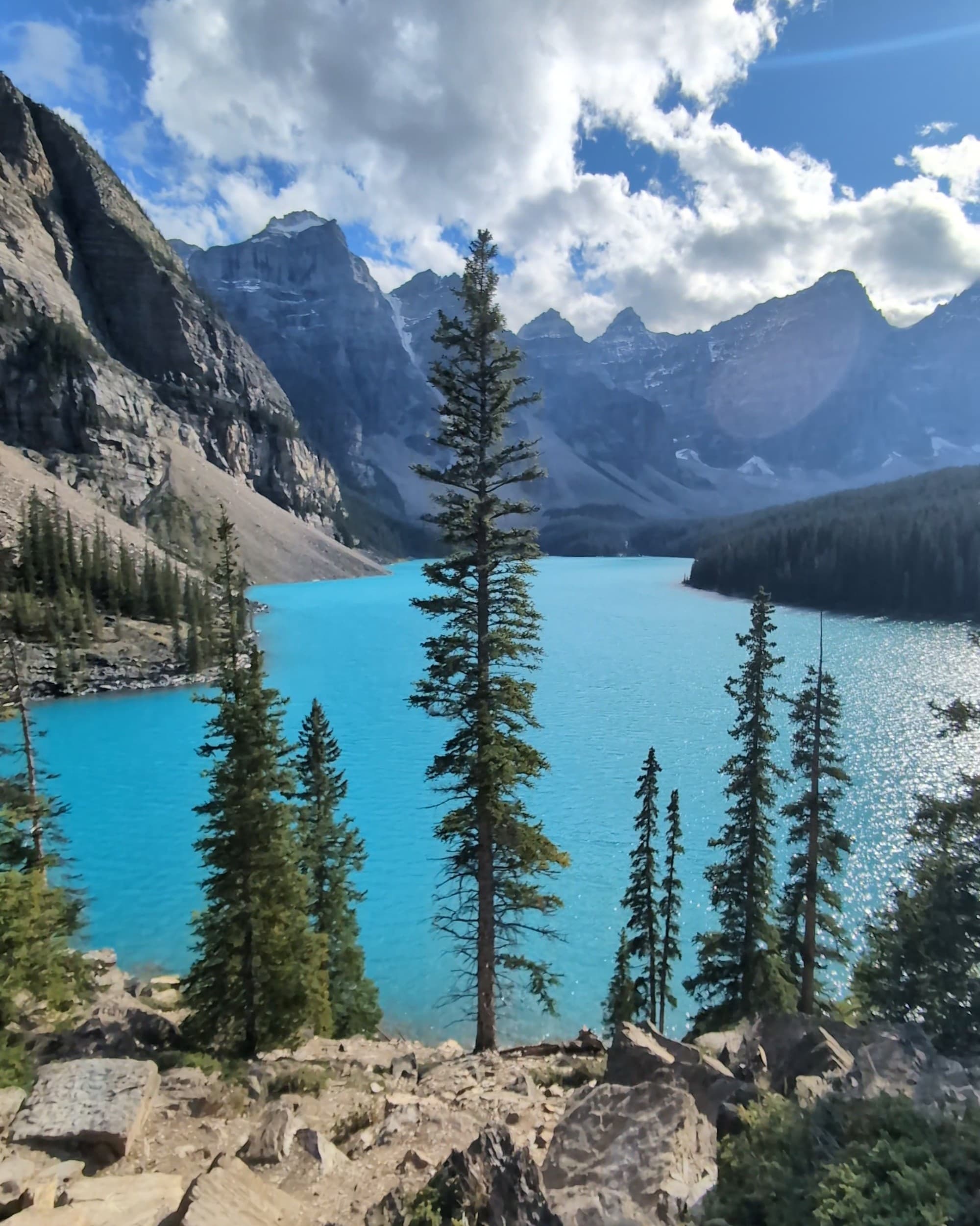 A scenic view of a turquoise-colored lake between mountain ranges during the daytime