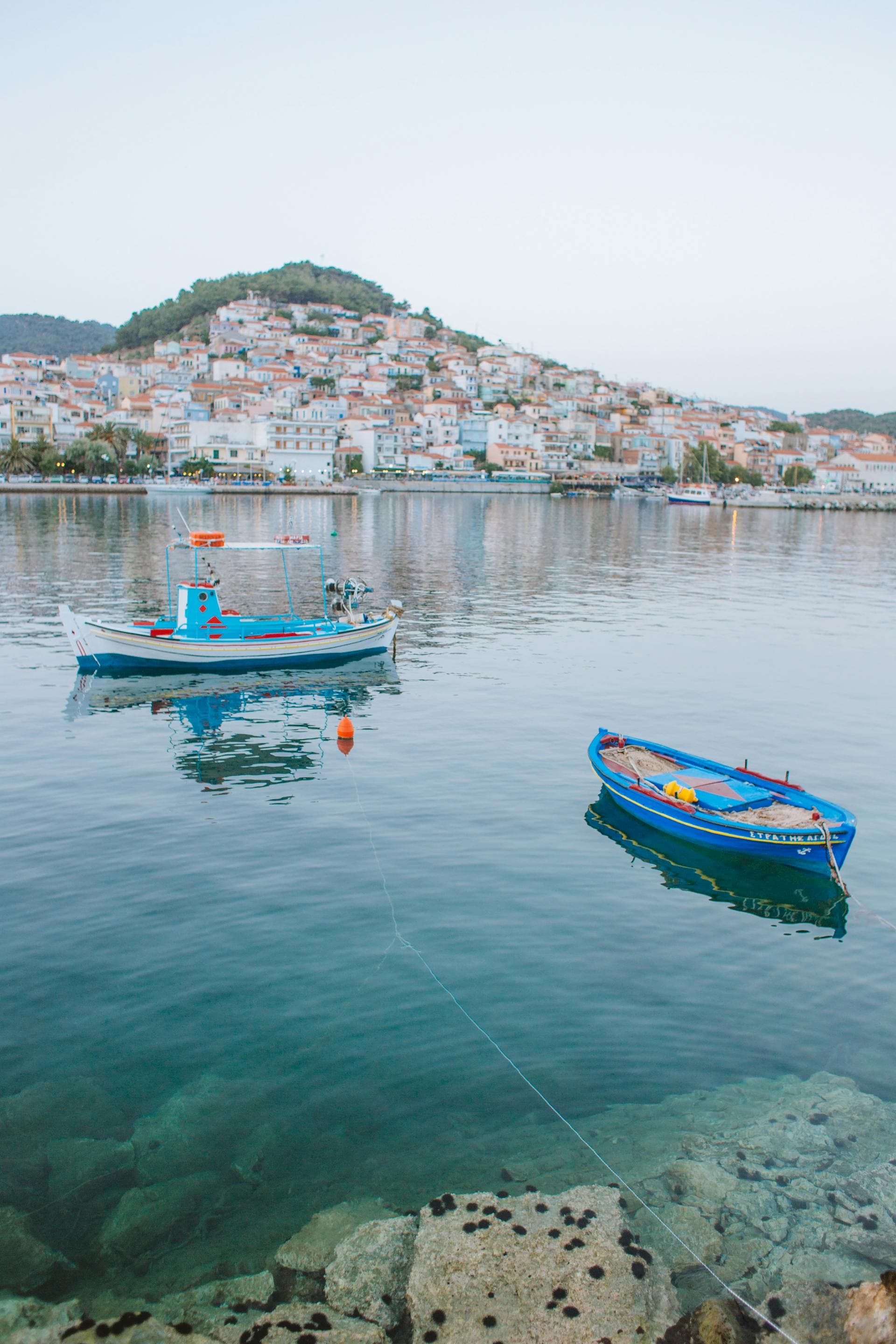 Boats with a view of the city of Greece on a hillside in the distance.