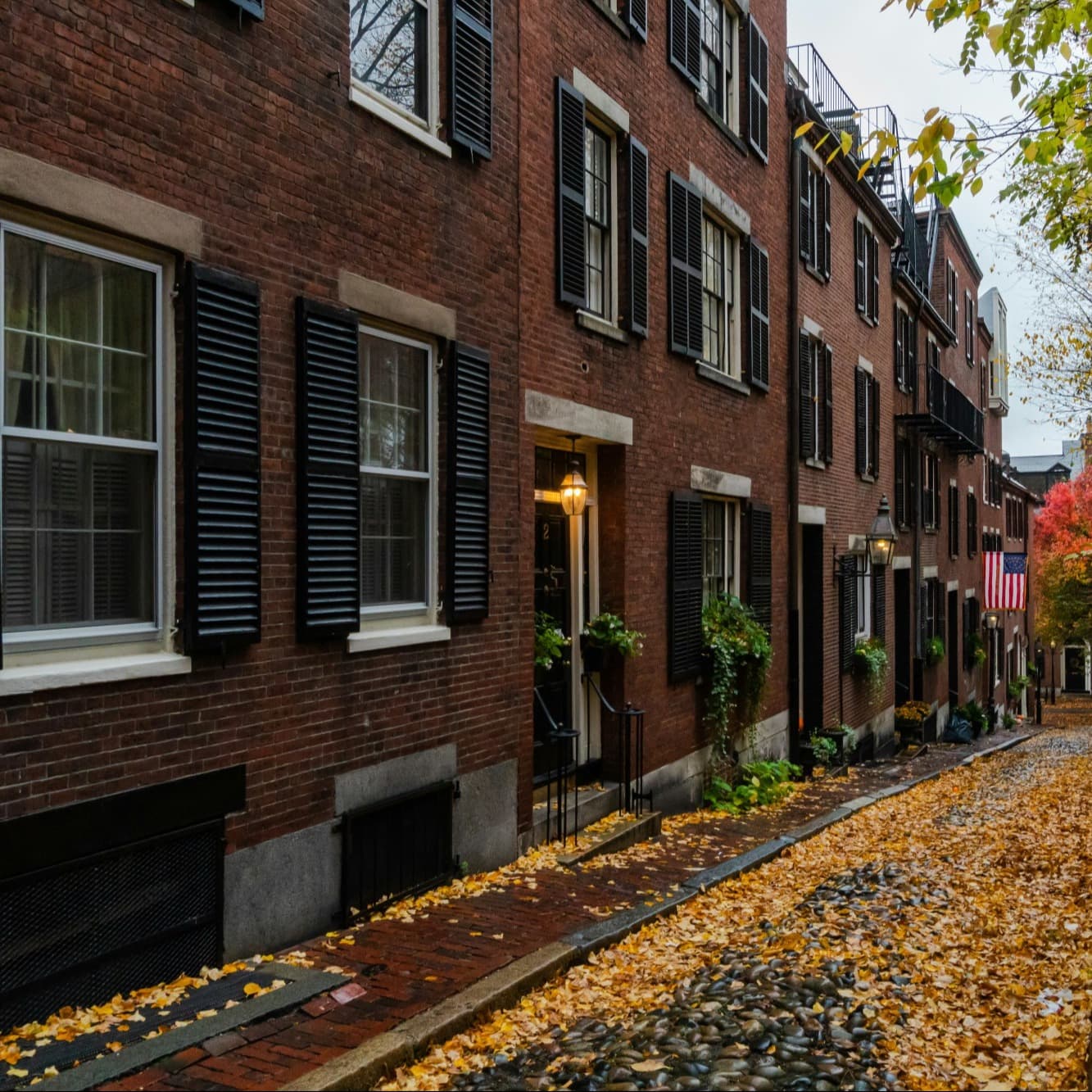 Pathway in front of red brick building with fall leaves.